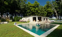 Piscina exterior rodeada de vegetación perenne y bosque en villa privada de Polonia, con diseño paisajístico adaptado al clima frío