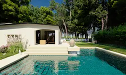 Piscina con fuente decorativa de cerámica y vegetación perenne en entorno residencial moderno en Polonia