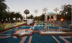 Jardín árabe iluminado con fuente geométrica, columnas ornamentales y vegetación tropical en Marrakech durante la noche