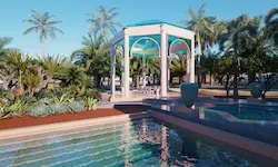 Zona de comedor exterior con piscina, columnas ornamentales y vegetación tropical en jardín árabe de lujo en Marrakech