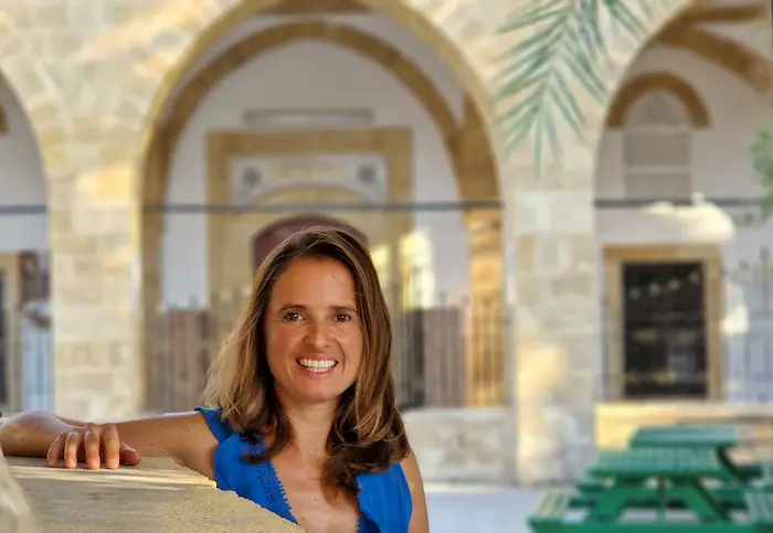 Kasia Porebska en espacio arquitectónico mediterráneo con arcos de piedra y vegetación, imagen de contacto profesional