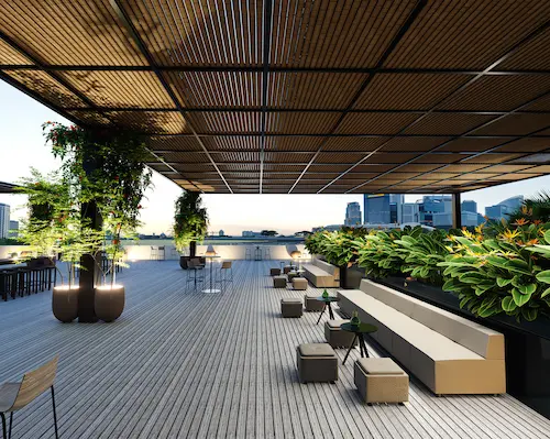 Lounge de ático elegante con pérgola, sofás beige y jardineras iluminadas.