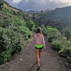 Kasia Porebska caminando por sendero de montaña rodeado de vegetación tropical en entorno natural en islas canarias